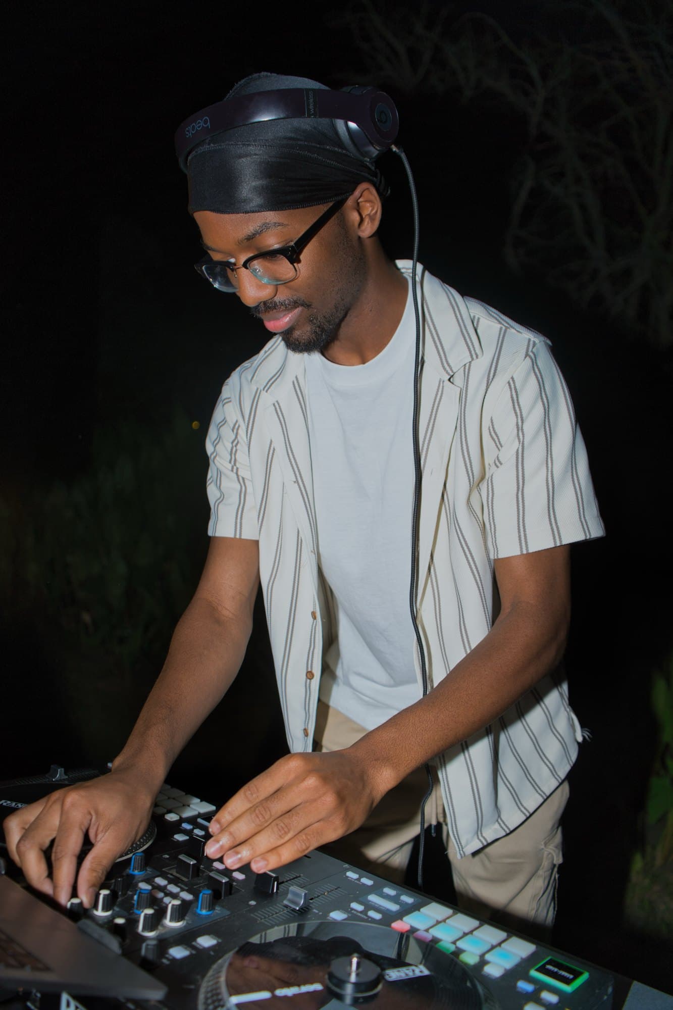 DJ in a striped shirt working the controller during a night set