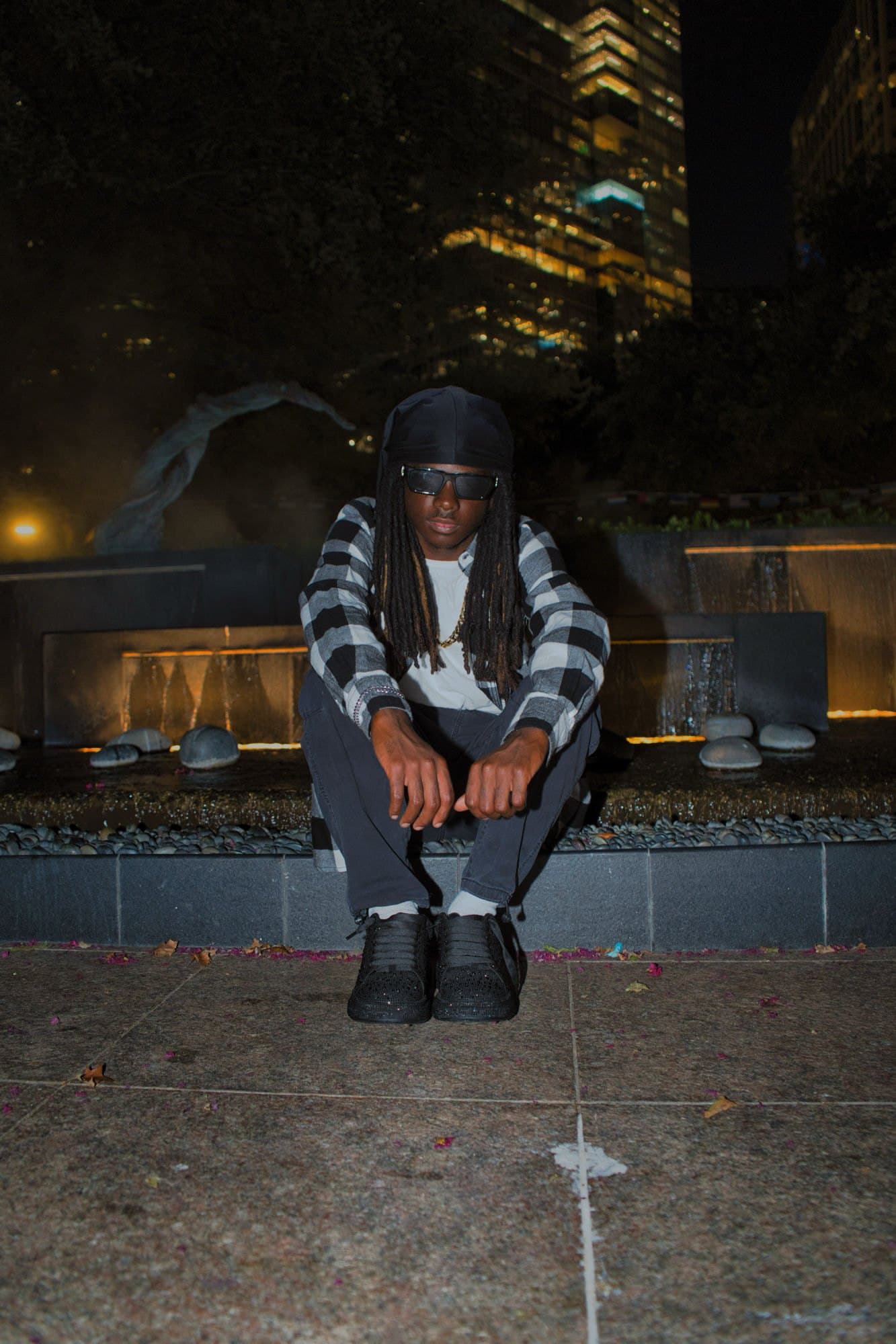 Night portrait seated at a downtown Houston fountain with the skyline lit behind
