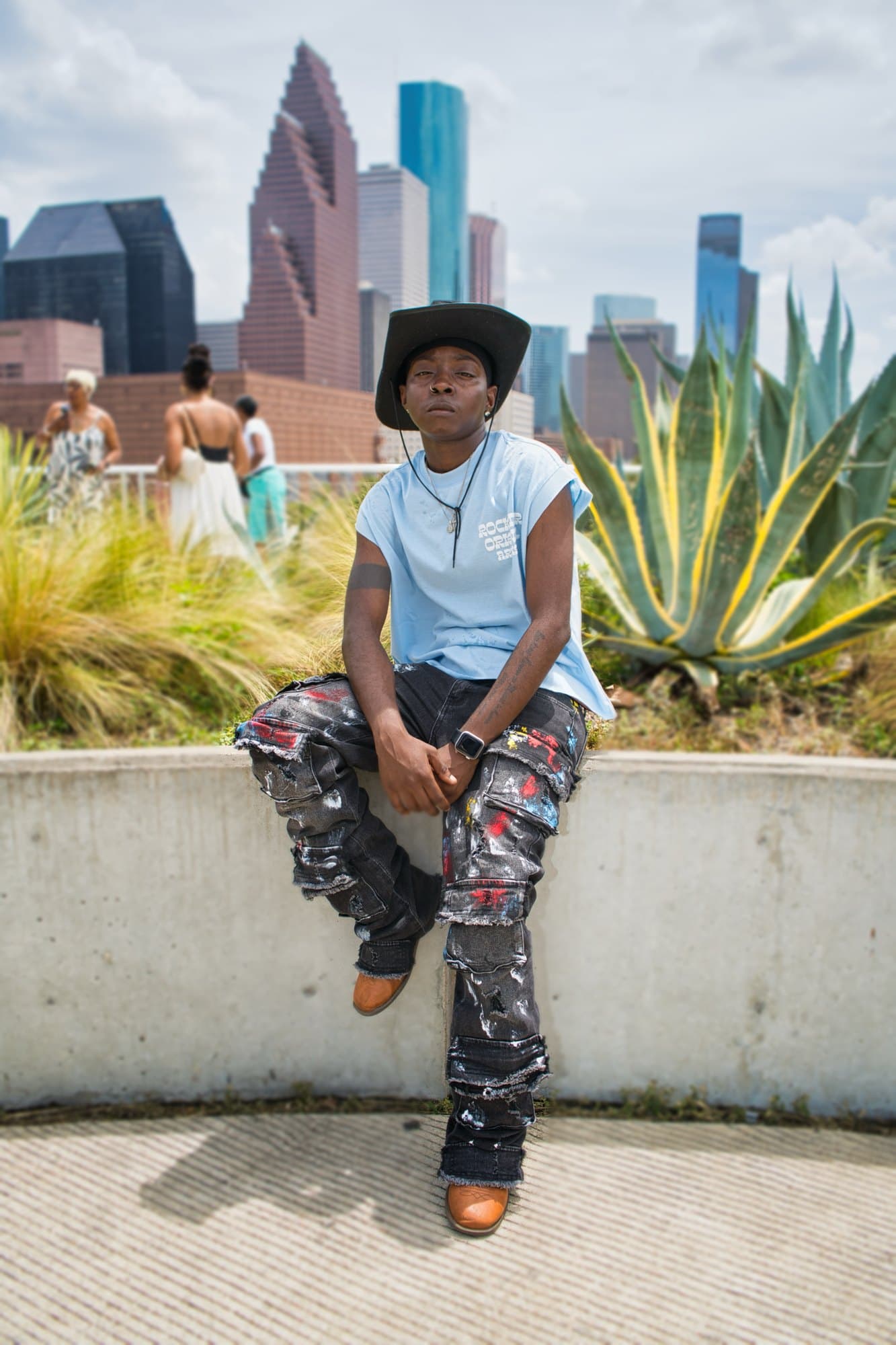 Rooftop portrait in a black cowboy hat with the downtown Houston skyline behind